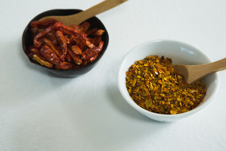 Dried red chili pepper and crushed red pepper in bowl on white background