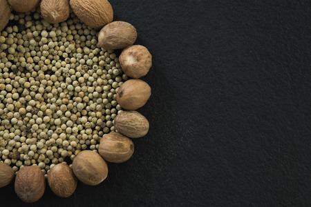 Overhead of white peppers surrounded with nutmegsの写真素材