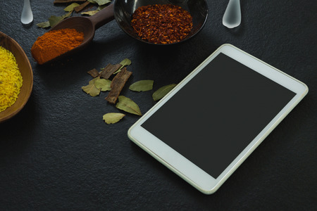 Close-up of spices powder with digital tablet on table