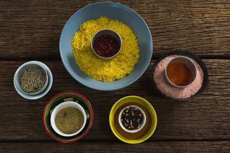 Rice in bowl with various spices and ingredients on wooden tableの写真素材