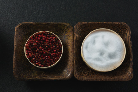Close-up of pink pepper and salt in a plateの写真素材