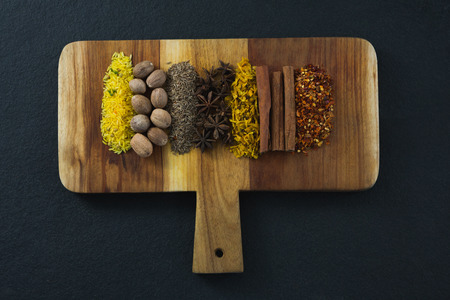 Various spices arranged in chopping board on black backgroundの写真素材