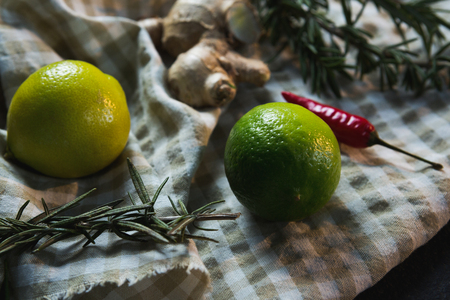 Close-up of sweet limes with rosemary and spices on table clothの写真素材