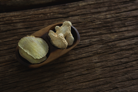 Dried ginger in a bowl on wooden tableの写真素材