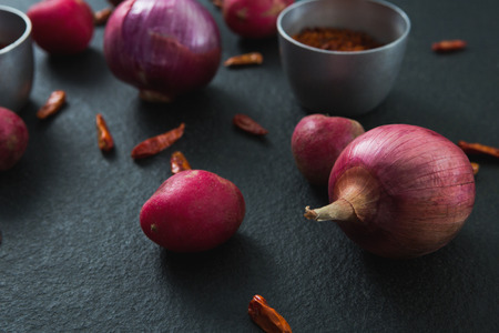 Close-up of onions and red pepper flakes on black backgroundの写真素材