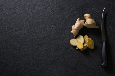 Overhead of sliced ginger with knife on black backgroundの写真素材