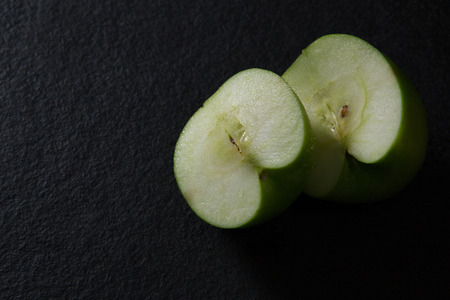Close-up of halved green apple on black backgroundの写真素材
