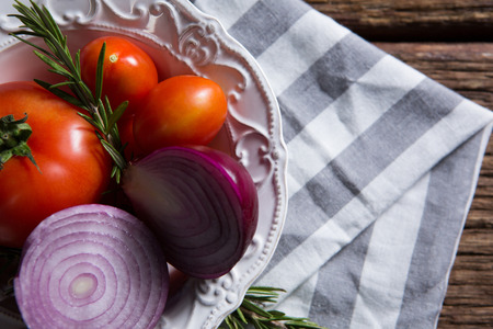 Close-up of fresh onions tomatoes and rosemary in bowlの写真素材