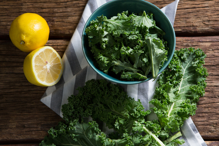 Overhead of mustard greens and lemon on wooden tableの写真素材