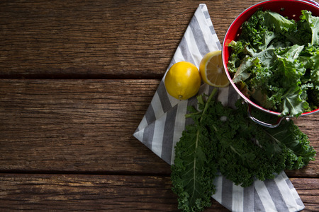 Overhead of mustard greens and lemon on wooden tableの写真素材