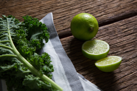 Close-up of mustard greens and lemon on wooden tableの写真素材