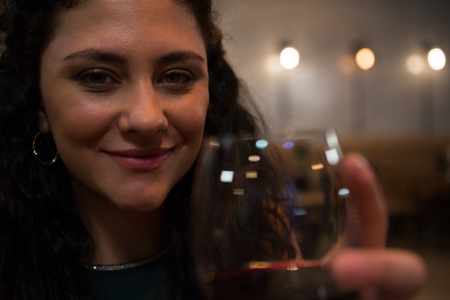 Portrait of beautiful woman holding red wine in restaurantの写真素材
