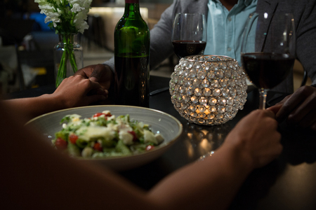 Couple holding hands while dining at table in restaurantの写真素材