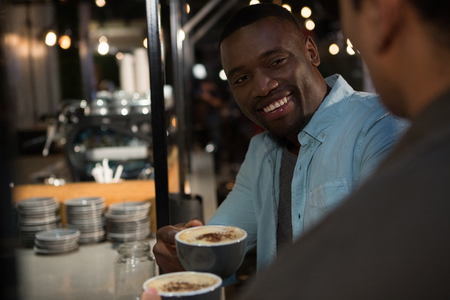 Happy man interacting while having coffee in restaurantの写真素材