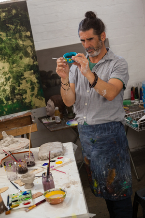 Attentive man painting bowl in class