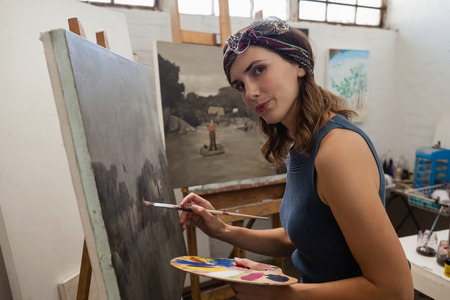 Portrait of woman painting on canvas in drawing classの写真素材