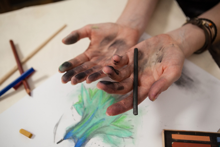 Woman holding charcoal pencil at tableの写真素材