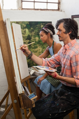 Man and woman painting on canvas in drawing classの写真素材