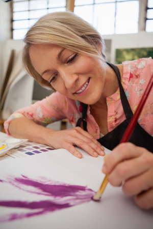 Woman painting in drawing book at drawing classの写真素材