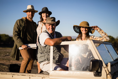 Portrait of happy friends enjoying in vehicle during safari vacation on a sunny day