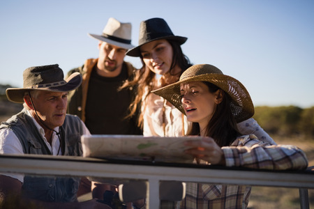 Friends looking at map in vehicle during safari vacationの写真素材