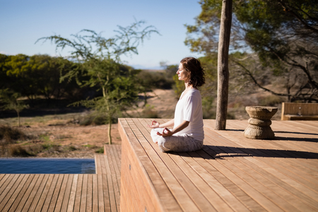 Woman practicing yoga on wooden plank on a sunny dayの写真素材