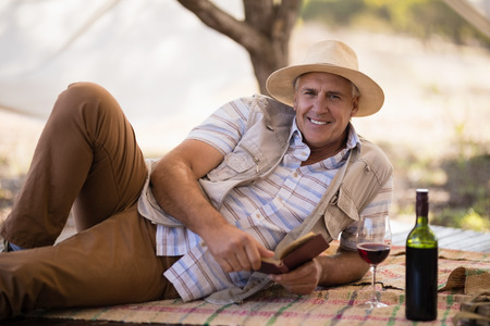 Portrait of happy man reading book in cottage during safari vacationの写真素材