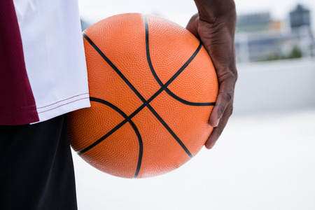 Mid section of player holding basketballの写真素材