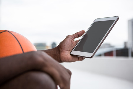 Basketball player using digital tablet on terraceの写真素材