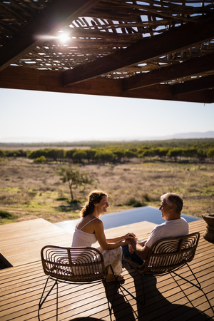 Senior couple sitting on chairs at the resort on a sunny dayの写真素材