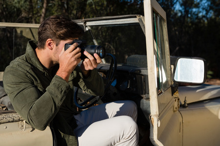 Man photographing while sitting in off road vehicleの写真素材