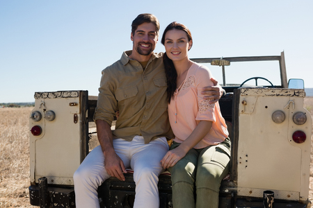 Portrait of smiling young couple sitting in off road vehicle on landscapeの写真素材