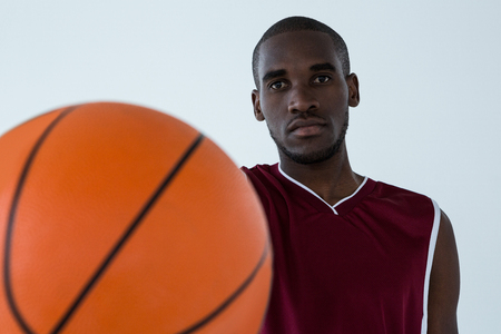 Confident player holding basketball against white backgroundの写真素材