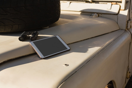 Digital tablet and binocular with spare tire on vehicle hoodの写真素材
