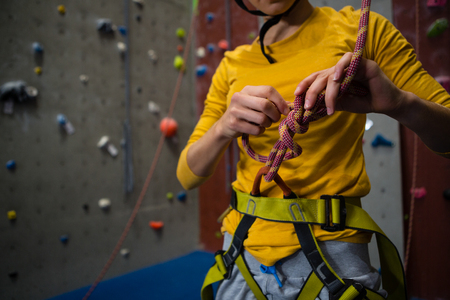 Midsection of female athlete tying rope while standing in health club