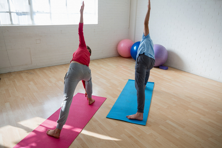 High angle view of instructor with female student practicing triangel pose in yoga studioの写真素材