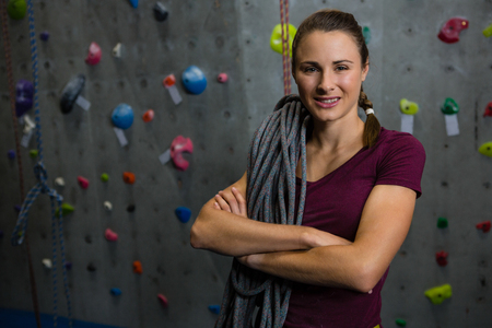 Portrait of smiling female athlete with rope standing in gymの写真素材