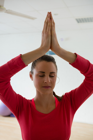 Young woman meditating while doing tree pose in yoga studioの写真素材