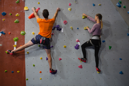Rear view of athletes rock climbing in health clubの写真素材