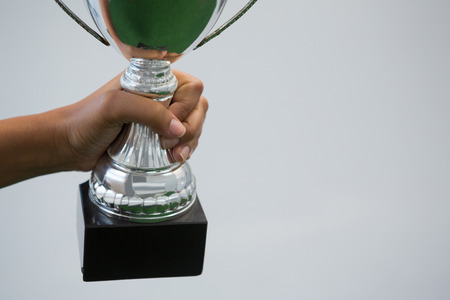Close-up of hand holding a trophy against white backgroundの写真素材