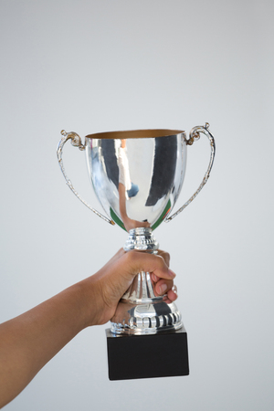 Close-up of hand holding a trophy against white backgroundの写真素材