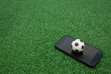 Close-up of football and mobile phone on artificial grassの写真素材