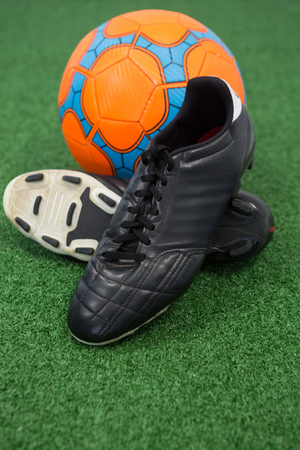 Close-up of football and cleats on artificial grassの写真素材