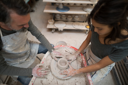 Male potter assisting female potter in pottery workshopの写真素材