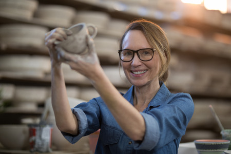 Portrait of female potter making cup in pottery workshopの写真素材