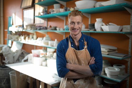 Portrait of male potter standing with arms crossed in pottery workshopの写真素材