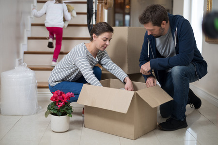 Couple opening cardboard boxes in living room at homeの写真素材