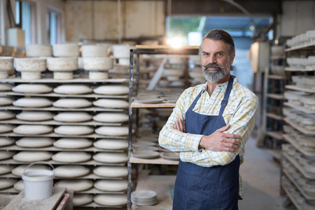 Portrait of male potter standing with arms crossed in pottery workshopの写真素材