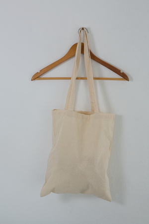 Beige bag on hanger against white wallの写真素材