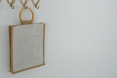 Bag hanging on hook against white wallの写真素材